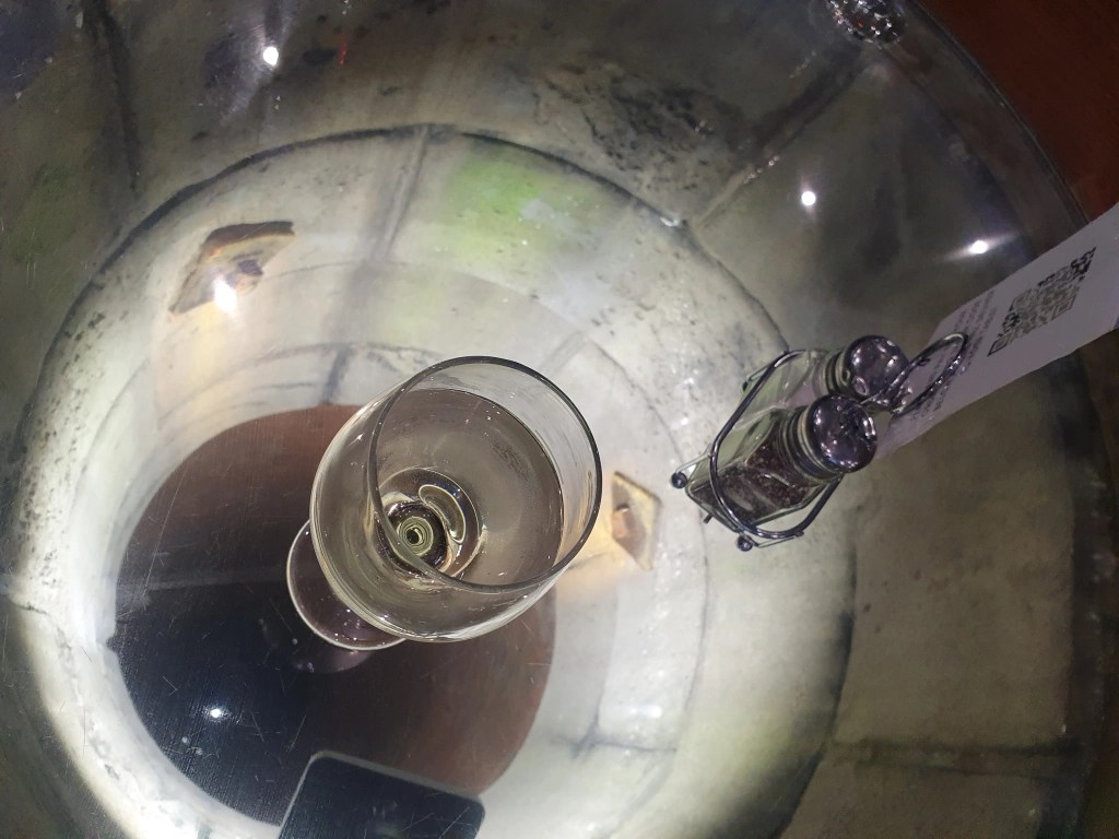 A glass table, with underlighting. An empty wine glass and salt and pepper shakers sit atop the table, also a QR code for ordering. Give a tunnel like effect.