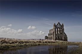 Countryside, by water, with the ruins of a church